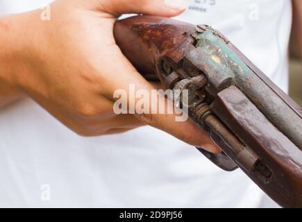 Horizontales Foto von Nahaufnahme Hand halten alte Waffe, selektive Fokus auf die Waffe. Stockfoto