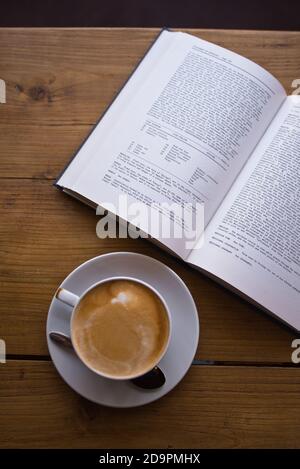 Flacher weißer Kaffee mit Buch im Coffee Shop auf dem Tisch - Kaffee Kunst - Latte Kaffee Stockfoto