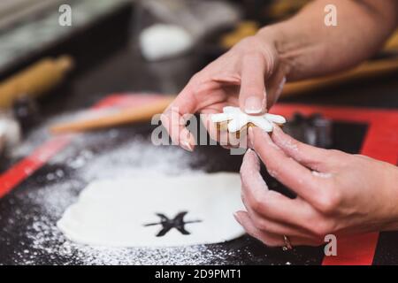 Frau schmückt weihnachten Lebkuchenkekse mit Puderzucker Schneeflocke Glasur. Weihnachtsgeschenk, hausgemachte Lebkuchen Stockfoto