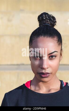 Vertikales Porträt einer attraktiven afroamerikanischen jungen Frau mit gefesselten Haaren Zurück in einem Pferdeschwanz trägt Sportkleidung und ernsthaft auf Die Kamera Stockfoto