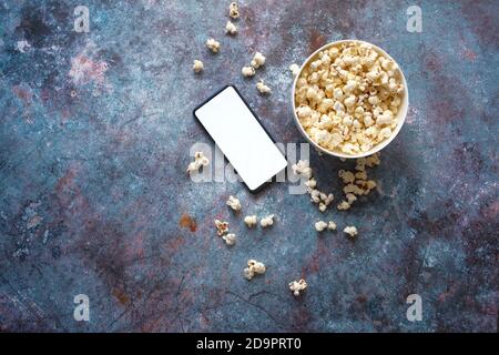 Draufsicht auf Smartphone und Popcorn auf dem Tisch Stockfoto