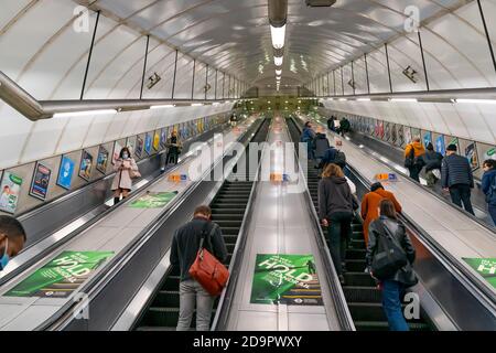 LONDON, ENGLAND - 23. OKTOBER 2020: Fahrtreppen der Londoner U-Bahn an der Holborn Circus Station während der Hauptverkehrszeit pendeln Passagiere mit Gesicht Stockfoto