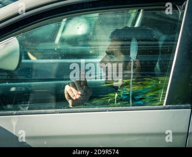 Bukarest/Rumänien - 10.17.2020: Mann raucht während der Fahrt in seinem Auto. Stockfoto