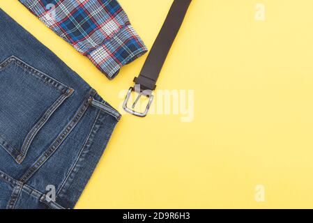 Mode Hintergrund, Jeans, Hemd, Gürtel. Denim-Style. Draufsicht. Männer Kleidung auf gelbem Hintergrund, Platz für Text. Stockfoto