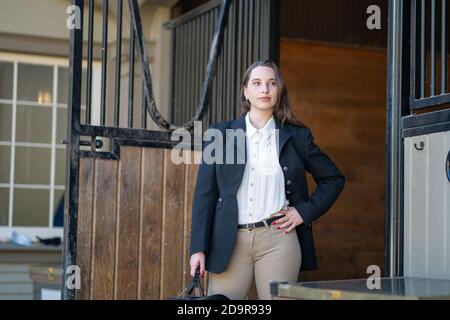 Reiterin Frau in englisch Reiten vor Stalltür stehend gekleidet Stockfoto