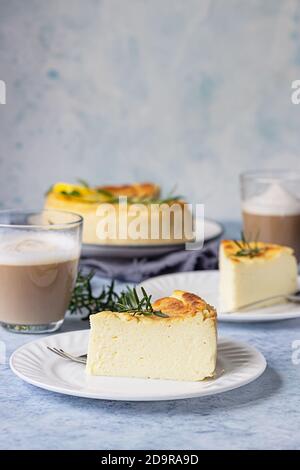 Käsekuchen mit Zitronenvanille, verziert mit Rosmarin-, Minze- und Zitronenscheiben. Ricotta keine Kruste Käsekuchen oder Kasserolle. Blauer Betonhintergrund. Stockfoto