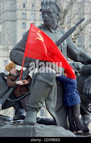 Kommunistische Anhänger besteigen eine Statue, die an den Aufstand gegen das zaristische Regime von 1905 erinnert, um die Flagge der UdSSR während der Anti-Jelzin-Proteste vor dem russischen parlamentsgebäude am 1. März 1993 in Moskau, Russland, zu hissen. Das russische Parlament stimmt darüber ab, ob es Präsident Boris Jelzin entheben soll. Stockfoto