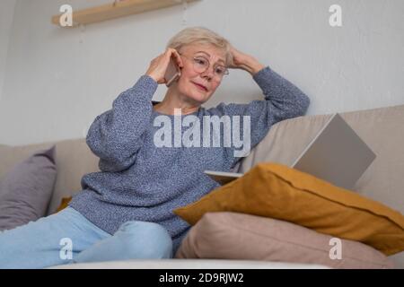 Kaukasische Erwachsene Frau, die auf dem Smartphone beim Coach sitzt Stockfoto