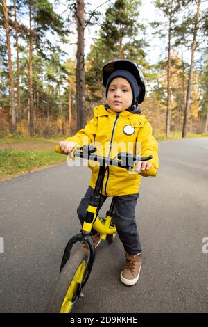 Adorable junge in Casualwear und Sicherheitshelm neben seinem stehen Laufrad Stockfoto