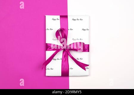 X-Mas Geschenk in Papier mit Weihnachts-Prints verpackt und mit schwarzem Band gebunden. Weihnachtsgeschenk Box auf weißem Hintergrund Stockfoto