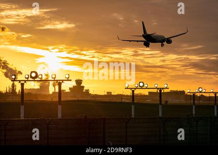 5. November 2020, Berlin, am Flughafen Berlin-Tegel 'Otto Lilienthal' (IATA-Code: TXL, ICAO-Code: EDDT) die Lichter gehen langsam aus. Die letzten Starts und Landungen finden statt. Die letzte Maschine startet am Sonntag, 8. November, in Tegel. Foto am Abend mit einem schönen Abendhimmel mit einem Landeflugzeug. Im Hintergrund der rauchende Kühlturm und der Schornstein aus dem Wärmekraftwerk Reuter West. Weltweite Nutzung Stockfoto