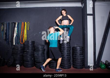 Workouts und Übungen für schwangere Frauen im Fitnessstudio. Kaukasische Athleten Bodybuilder, Ehepaar Ehemann und Ehefrau genießen Schwangerschaft und posieren nach Stockfoto