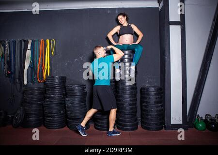 Schwangerschaftszeit bei sportlich starken muskulösen Frauen. Gemeinsame Workouts und Übungen des Paares während der Schwangerschaft in der Turnhalle. Mann und schwangere Frau Stockfoto
