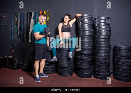 Schwangerschaftszeit bei sportlich starken muskulösen Frauen. Gemeinsame Workouts und Übungen des Paares während der Schwangerschaft in der Turnhalle. Mann und schwangere Frau Stockfoto