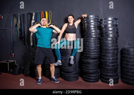 Workouts und Übungen für schwangere Frauen im Fitnessstudio. Kaukasische Athleten Bodybuilder, Ehepaar Ehemann und Ehefrau genießen Schwangerschaft und posieren nach Stockfoto