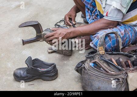 Indische lokale Schuster Reparatur Schuhe neben der Straße von Hand mit Werkzeugen in traditioneller Weise. Natürliche Schuss Darstellung der täglichen Arbeit eines regelmäßigen Schuster. Stockfoto