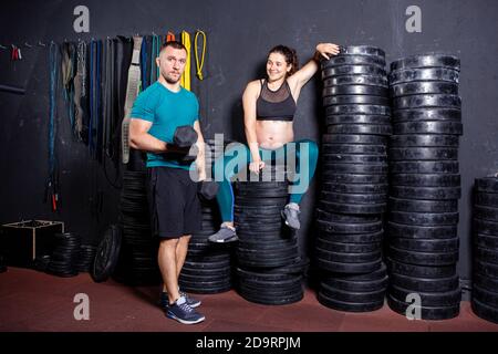 Workouts und Übungen für schwangere Frauen im Fitnessstudio. Kaukasische Athleten Bodybuilder, Ehepaar Ehemann und Ehefrau genießen Schwangerschaft und posieren nach Stockfoto