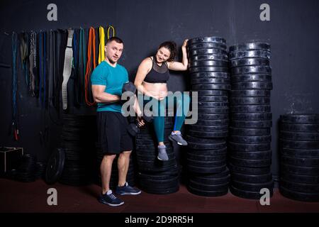 Workouts und Übungen für schwangere Frauen im Fitnessstudio. Kaukasische Athleten Bodybuilder, Ehepaar Ehemann und Ehefrau genießen Schwangerschaft und posieren nach Stockfoto