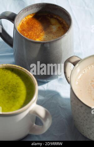Veganes Kakao-Getränk mit Matcha, Kurkuma und Zimt auf blauem Hintergrund Nahaufnahme. Milchgetränk Stockfoto