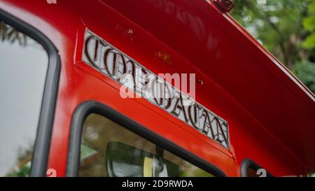 Coyoacan-Schild auf einem roten Trolley-Auto mit verschwommenen Bäumen Im Hintergrund Stockfoto