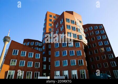 Düsseldorf (Medienhafen), Deutschland - 7. November. 2020: Blick auf rotes Gehry-Haus mit moderner futuristischer Architektur, Fernsehturm Hintergrund Stockfoto