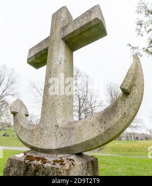 Ein Grabstein in Form eines Schiffsankers. Es ist kein Text vorhanden. Dies ist eine Ansicht mit niedrigem Winkel, die nach oben zeigt. Es gibt etwas Moos auf dem Grabstein. Stockfoto