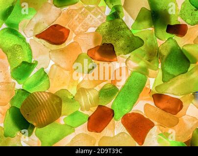 Stapel von natürlichen Strand Glas roh und natürlich, wie es vom Strand gesammelt wurde. Es gibt grüne, braune und cremeweiße Stücke. Hintergrundbeleuchtung. Stockfoto