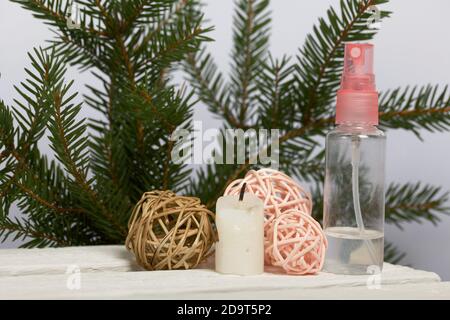 Kerze auf weißen Kiefernbrettern. In der Nähe sind Rattanbälle. Vor dem Hintergrund von Tannenzweigen. Stockfoto