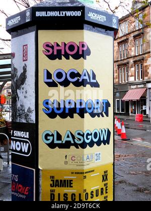 Eine Werbesäule auf der Byres Road in Glasgow fordert die Menschen auf, vor Ort einzukaufen und Glasgow während dieser Coronovirus-Pandemie zu unterstützen, die alle in Großbritannien getroffen hat und dazu führt, dass die Bevölkerung sicher und zu Hause bleibt, um eine weitere Ausbreitung zu verhindern. Glasgow Oktober 2020. ALAN WYLIE/ALAMY© Stockfoto