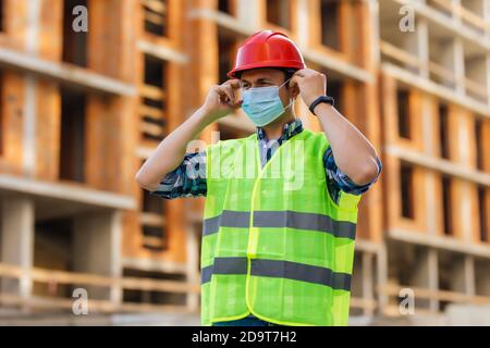 Ingenieur in Schutzhelm und medizinische Maske auf der Baustelle Während der Coronavirus-Epidemie Stockfoto
