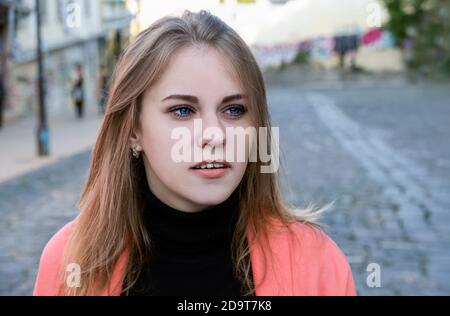 Porträt einer jungen Frau in einem leuchtend rosa Jacke Spaziergang die Straße entlang an einem warmen Herbsttag Stockfoto