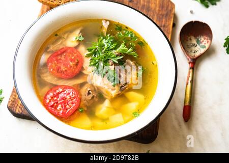 Fischsuppe mit Karpfen, Kartoffeln, Petersilie, Tomaten in Emaille-Schüssel steht auf einem Brett Stockfoto