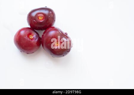 Drei frische Kirschen auf weißem Hintergrund mit ein paar Wassertropfen auf sie mit Kopie sapce an der Richtig Stockfoto