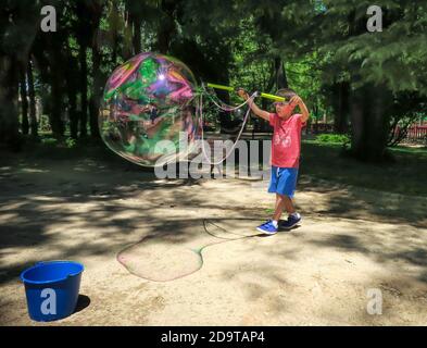 Junge macht riesige Seifenblasen in einem Park Stockfoto