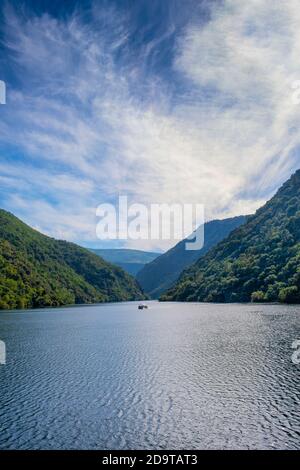 Schlucht des Flusses Sil in der Ribeira Sacra von Lugo, Spanien.Flusslandschaft zwischen Bergen mit terrassierten Weinbergen mit einem Boot im Hintergrund und Stockfoto