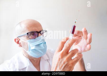 Arzt mit einer Spritze Blut in der Hand klopfen Luft aus Stockfoto