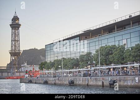 Barcelona, Spanien, September 2019. Seilbahnturm, der den Hafen vom Meer aus mit dem maremagnum Gebäude auf der rechten Seite überquert. Stockfoto