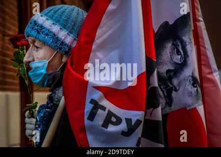 Moskau, Russland. 7. November 2020 EINE Frau mit Gesichtsmaske hält ein Transparent mit einem Porträt von Wladimir Lenin während einer Prozession, die von Kommunisten Russlands anlässlich des 103. Jahrestages der bolschewistischen Revolution vom 1917. Oktober auf dem Roten Platz im Zentrum von Moskau, Russland, inszeniert wurde Stockfoto