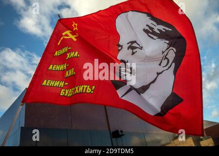 Rote Fahne mit dem Porträt des Revolutionsführers Wladimir Lenin und der Inschrift "Lenin lebte, Lenin lebt, und Lenin wird immer leben" auf dem Hintergrund des Leninschen Mausoleums auf dem Roten Platz im Zentrum von Moskau, Russland Stockfoto