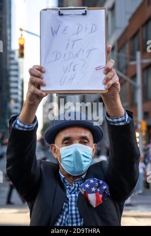 New York, USA. November 2020. Die Menschen tragen Gesichtsmasken, während sie auf dem New Yorker Times Square feiern, nachdem die Nachricht ausbrach, dass der ehemalige Vizepräsident Joe Biden die US-Präsidentschaftswahlen gewonnen hat. Biden besiegte Präsident Donald Trump, um zum 46. Präsidenten der Vereinigten Staaten zu werden, und Kamala Harris wird die erste weibliche Vizepräsidentin sein. Kredit: Enrique Shore/Alamy Live Nachrichten Stockfoto