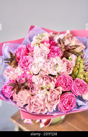 Lila und rosa Bouquet mit der Blume der Artischocke. Schöne Blumen auf Holztisch. Floristik-Konzept. Frühlingsfarben. Die Arbeit des Floristen Stockfoto