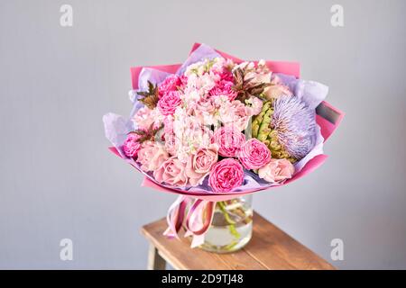 Lila und rosa Bouquet mit der Blume der Artischocke. Schöne Blumen auf Holztisch. Floristik-Konzept. Frühlingsfarben. Die Arbeit des Floristen Stockfoto