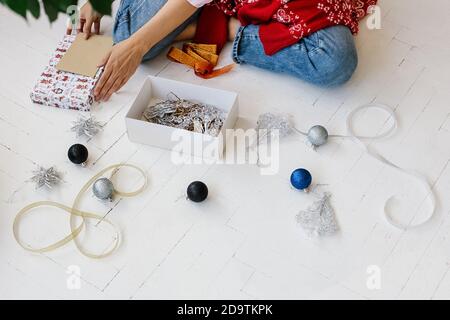 Frau Dekoration weihnachtsgeschenk. Bunte Bälle und Weihnachtsdekorationen auf dem Boden in der Nähe, Blick von oben. Stockfoto