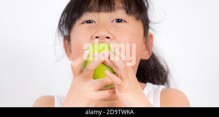 Bild von einem jungen asiatischen Mädchen mit schwarzen Haaren essen gesunde grüne Apfelfrucht und Vitamin C für Ernährung oder Ernährung in den weißen Hintergrund. Stockfoto