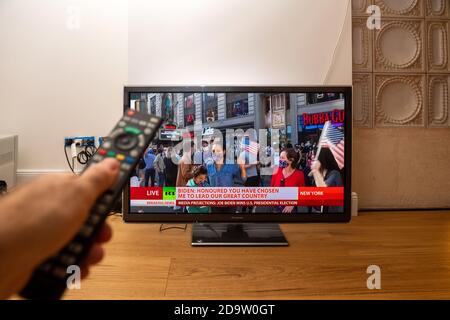 Paris, Frankreich - Nov 7, 2020: Die Menschen feiern, wie man sie im Wohnzimmer-tv auf dem Holzboden sieht, mit den neuesten Nachrichten, dass der demokratische Präsidentschaftskandidat Joe Biden die Wahl anscheinend gewonnen hat Stockfoto