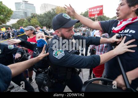 Austin, Texas, USA. November 2020. Ein Polizeibeamter aus Austin trennt Demonstranten, während Gruppen, die Joe Bidens Wahlsieg feiern, mit Pro-Trump-Anhängern im Texas Capitol zusammenprallen, wo die Polizei von Austin und die texanischen Truppen versuchten, die beiden auseinander zu halten. Der Protest zählte einige hundert, nachdem Biden am 7. November 2020 zum Sieger des Präsidenten der Vereinigten Staaten erklärt wurde. Kredit: Bob Daemmrich/Alamy Live Nachrichten Stockfoto