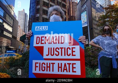 Eine Frau trägt eine Gesichtsmaske hält ein Plakat, das fordert Gerechtigkeit Kampf Hass während der Feier von Bidens Sieg als 46. US-Präsident am Union Square in New York sagt. Stockfoto