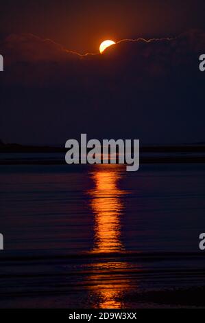 Der Erntemond steigt über Wolken auf und schafft Höhepunkte auf atlantischen Gewässern Stockfoto