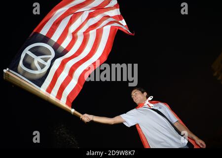 New York City, USA. November 2020. Ein Mann schwenkt eine Flagge mit einem Friedenssymbol, während die Menschen im Washington Square Park zusammenkommen, um zu feiern, nachdem die Medien Joe Biden Gewinner der US-Präsidentschaftswahlen 2020 erklärt haben, New York, NY, 7. November 2020. Der Demokrat Joe Biden besiegte Präsident Donald Trump, um die 46. Präsidentin der Vereinigten Staaten zu werden, und Kamala Harris, die erste Frau Vizepräsidentin, nachdem berichtet wurde, dass Biden Pennsylvania mit 20 Wahlstimmen gewann.“ (Anthony Behar/Sipa USA) Quelle: SIPA USA/Alamy Live News Stockfoto