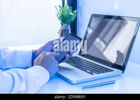 Seitenansicht eines Mannes mit einem Smartphone im Innenraum, Rückansicht des Geschäftsmannes mit dem Handy am Bürotisch, junge männliche Studenten Stockfoto